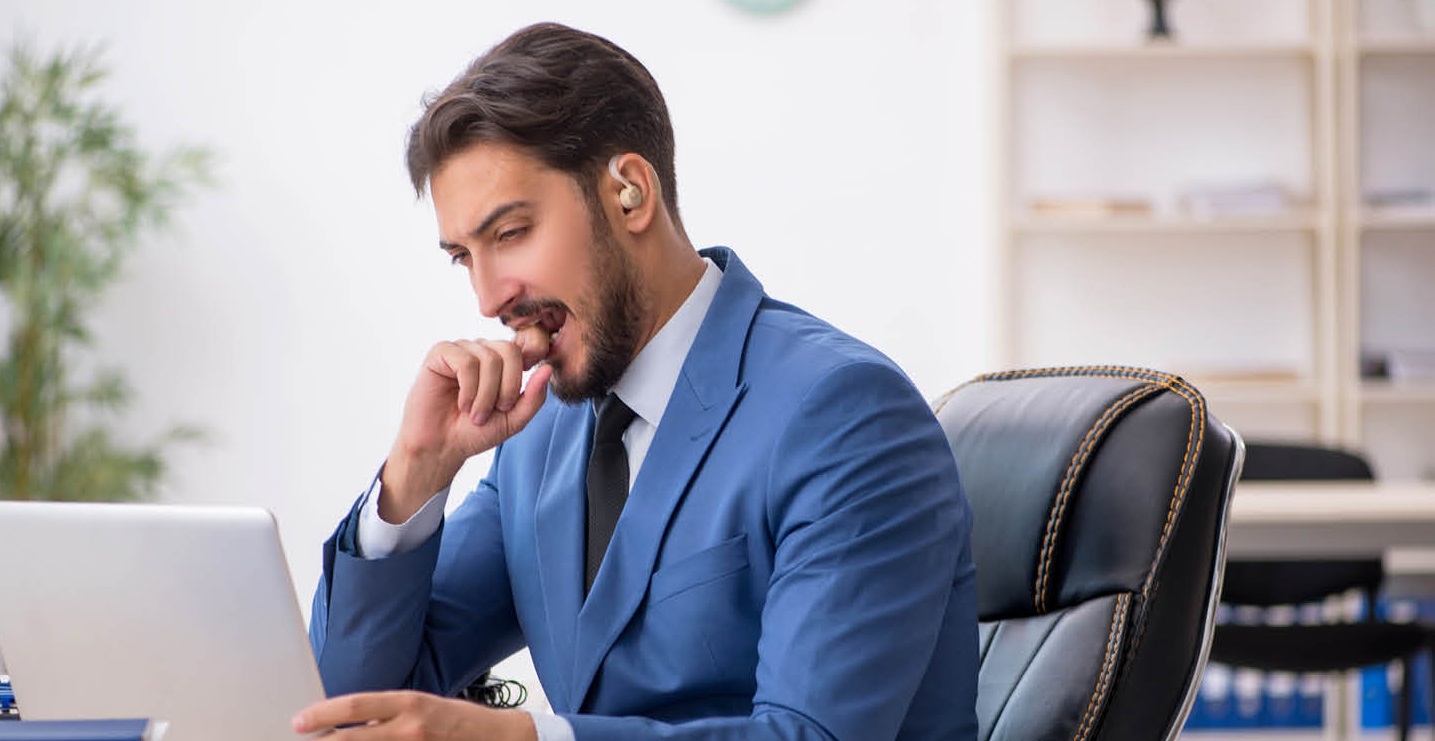 A businessman wearing a headphone and concentrating on his work on a laptop.