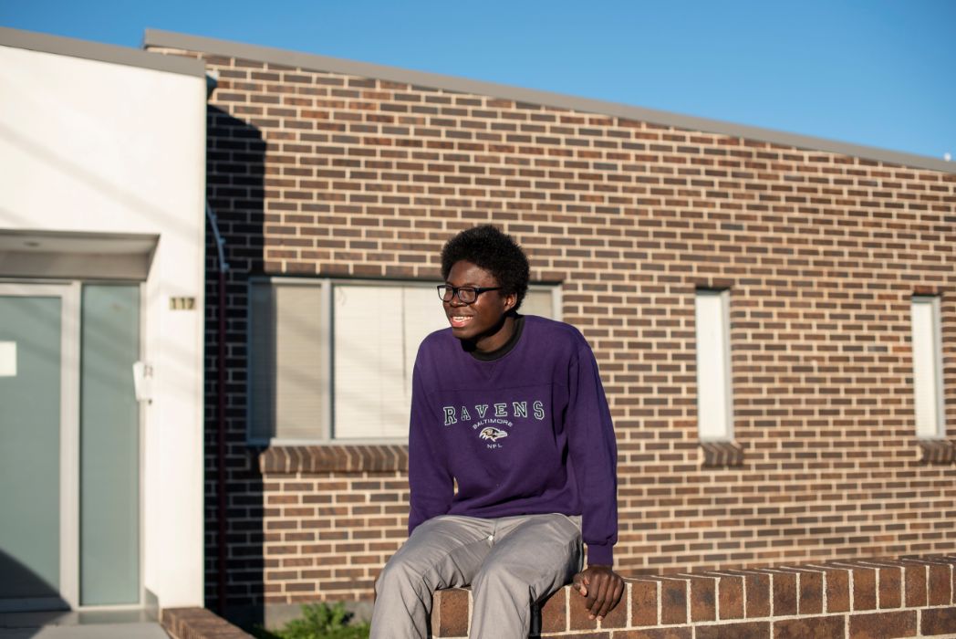 Daniel pictured sitting on the edge of a brick fence.