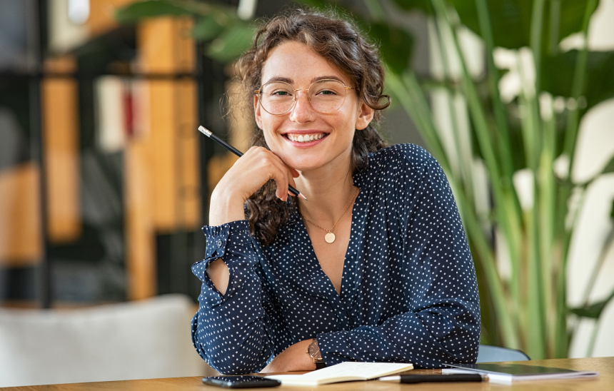 A happy lady sitting down, wearing business attire.
