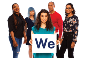 A group of people. A person at the front is holding a card that reads "We".