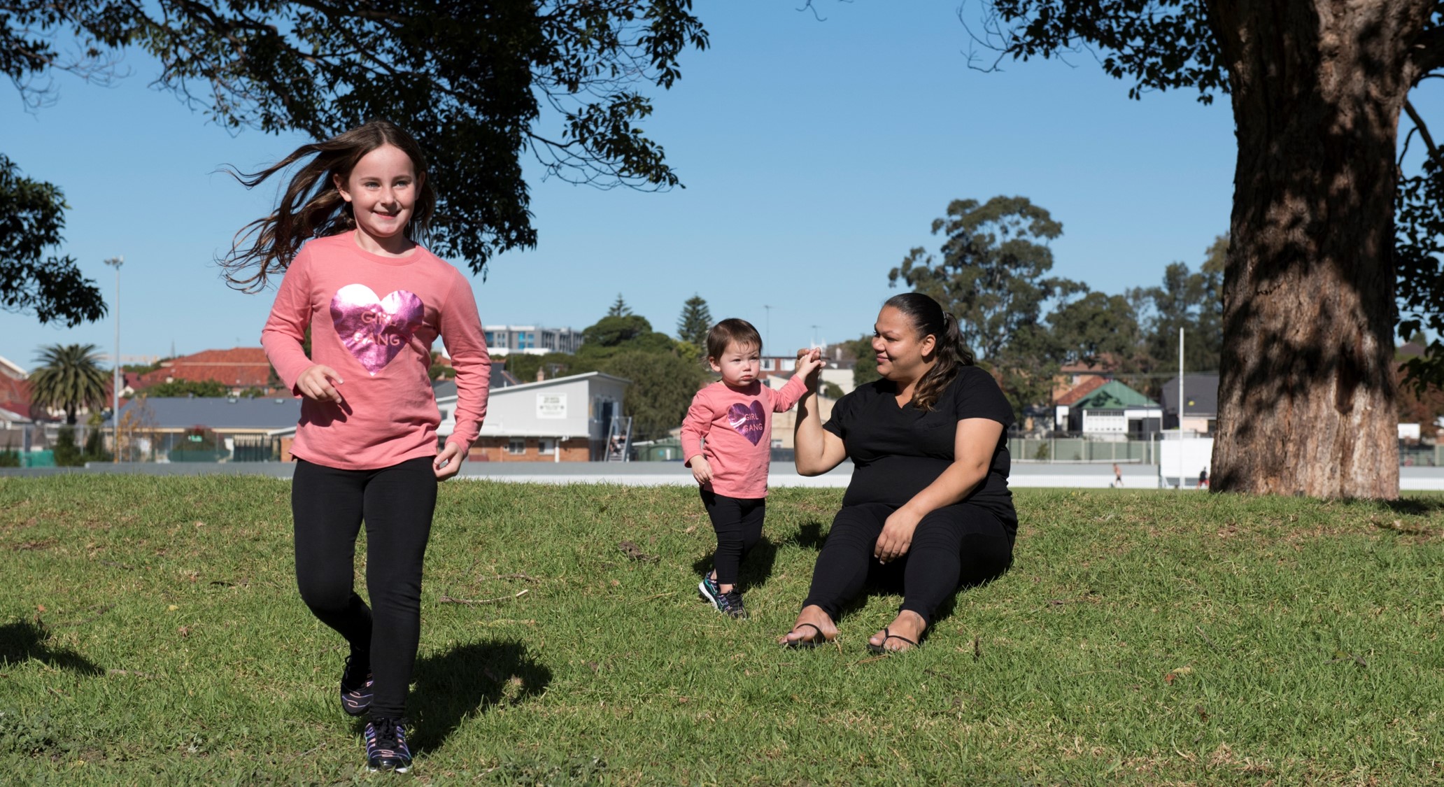 Adult woman playing with two children in a park