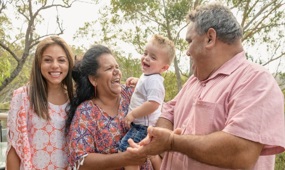 A family laughing together holding a young child