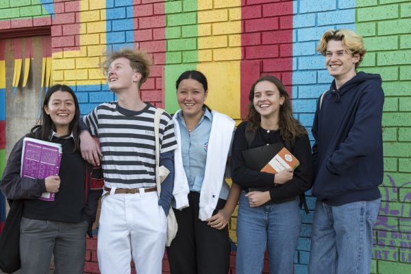 Teenagers stand together laughing at school